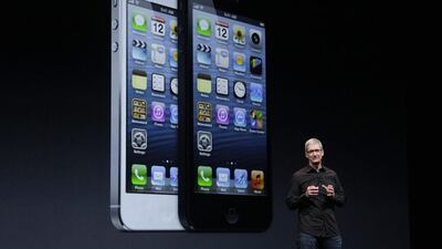 Apple CEO Tim Cook speaks in front of an image of the iPhone 5. Jeff Chiu / AP Photo