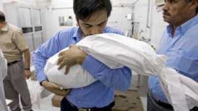 Hassan Bakari carries the body of his son Suhail at Sheikh Zayed Mosque in Ajman yesterday.