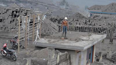 A resident cleans up ash that damaged houses and farms in Malang, East Java, on February 16, 2014, following the volcanic eruption of Mount Kelud on February 13. Three Indonesian airports reopened February 15, while four others remained closed, officials said, after the eruption killed four people and forced mass evacuations. Aman Rochman / AFP photo