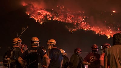 Firefighters attempt to extinguish a wildfire as smoke and flames rise from a forested area in the Gursu district of Bursa early on July 27, 2025. (Photo by ONUR YURTSEVER / AFP)