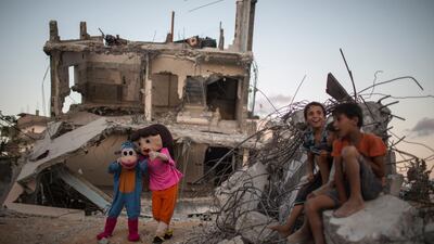 Palestinians dressed in costumes perform during an event for children in front of destroyed houses in Beit Hanun in the Gaza Strip, August 30, 2015. The occasion of the first anniversary of the 50-day war between Israel and Hamas militants in the summer of 2014. One year ago, a new war erupted between Israel and Palestinians in the Gaza Strip, the third in six years. In the course of the conflict the longest, deadliest and most destructive, 2,251 Palestinians were killed, including 551 children. More than 10,000 were wounded and 100,000 were left homeless. On the Israeli side 73 people were killed, of whom 67 were soldiers. Up to 1,600 were wounded, according to the United Nations. Wissam Nassar