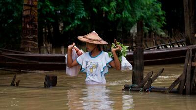 A young woman carries provisions as she wades through a flooded street in Shwegyin, Bago region, on August 2, 2018. Fears that embankments could burst under fresh rains mounted in flooded southeastern Myanmar, where some 150,000 people have been forced from their homes and a dozen people killed. / AFP PHOTO / YE AUNG THU