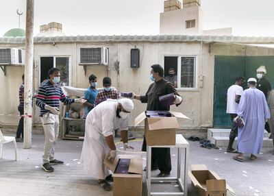 Volunteers hand out the iftar meals to workers. Reem Mohammed / The National