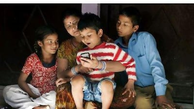 Meenu Mishra listens to a segment of the GGSS programme with her children Muskan, 8. Gagan, 6, and Abishek, 14 , at their home in India. The GGSS initiative by the Sesame Street foundation beams radio programmes into slums using mobile phones to promote healthy habits to children and their parents.