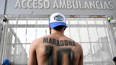 A supporter of Argentine former football star and coach of Gimnasia y Esgrima La Plata Diego Maradona displays his tattoo, outside the hospital where Maradona will undergo brain surgery for a blood clot, in Olivos, Buenos Aires province. AFP