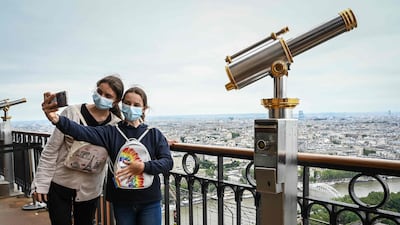 Visitors take a selfie as they visit the Eiffel Tower. The landmark reopened to visitors on July 16, nine months after it was forced to close by the pandemic.