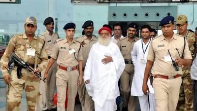 Indian spiritual guru Asaram Bapu, wearing a red cap, arrives at Bhopal airport.