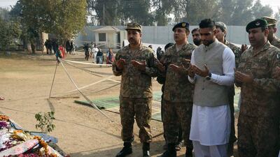 Amir Khan prays with Pakistani military officials at the school in Peshawar on Monday. A Majeed / AFP