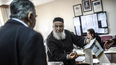 A Turkish man shows another man how to cast his vote in Istanbul on March 23, 2014, ahead of nationwide elections for mayors and local assemblies. Bulent Kilic / AFP