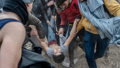 Migrants carry an injured man away after being shot by Greek security officer after trying to get on the Greek side of the Greece-Turkey border near Pazarkule in Edirne, Turkey. AFP