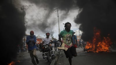 Protesters run past burning tyres during a march demanding the resignation of Haiti's President Jovenel Moise in Port-au-Prince, Haiti. REUTERS