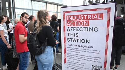 Travellers stand next to a strike action notice at St Pancras Station in London on Tuesday. EPA