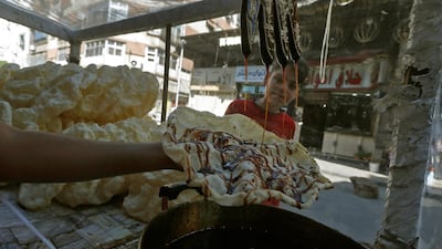 A Syrian vendor spreads grape molasses on a pancake, a traditional sweet known as al-Naem and commonly served during Ramadan, the Muslim fasting month. AFP