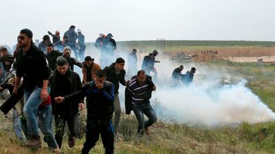 Palestinian protesters run from tear-gas during clashes near the border with Israel east of Gaza City on March 30, 2018. Mahmud Hams / AFP