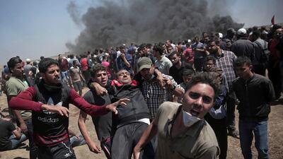 Palestinian protesters carry an injured man who was shot by Israeli troops during a deadly protest at the Gaza Strip's border with Israel. Adel Hana / AP