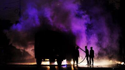 Pakistani firefighters extinguish a burning vehicle. It was set on fire by protesters angry at killings in their district of Karachi. Asif Hassan / AFP Photo