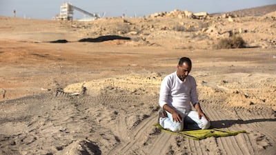 Achmed, 43, prays in the late afternoon sun before driving a truckload of 38 tons of phosphate to Ashdod from the industrial area of Rotem, where phosphate is mined, on February 4, 2018. He says the compound gives him headaches but that he has got used to the irritation it also causes his eyes. Heidi Levine
