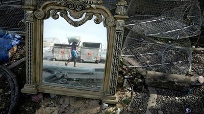 A discarded mirror reflects a fisherman as he loads his boat with a bait bag of bread in the Jumeirah 4 Harbour near Dubai Offshore Sailing Club. Antonie Robertson / The National