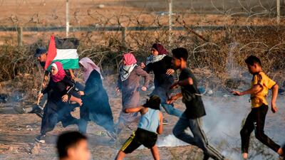Palestinian protesters run from tear gas fired by Israeli forces along the border east of Bureij in central Gaza on November 1, 2019. AFP