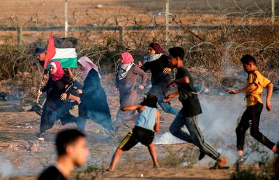 Palestinian protesters run from tear gas fired by Israeli forces along the border east of Bureij in central Gaza on November 1, 2019. AFP