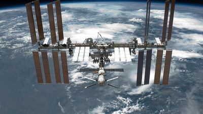 A view of the International Space Station backdropped by Earth. The station has four large, maroon-coloured solar array wings, two on either side of the station, mounted to a central truss structure. Further along the truss are six large, white radiators, three next to each pair of arrays. In between the solar arrays and radiators is a cluster of pressurised modules arranged in an elongated T shape, also attached to the truss. A set of blue solar arrays are mounted to the module at the aft end of the cluster. Wikicommons
