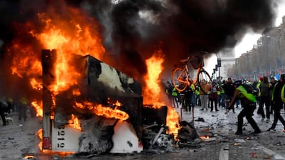 A man throws a cycle onto a burning truck during a protest of yellow vests on the Champs Elysees in Paris on November 24, 2018. AFP