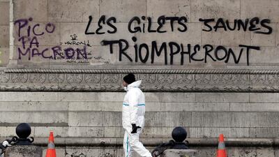 A Paris city worker passes by a graffiti sprayed on the side of the Arc de Triomphe which reads 'the yellow vests will triumph' as police and city employees assess the damages of the 'Yellow Vests' protest on Saturday. EPA
