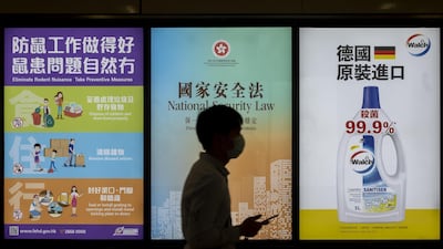 A pedestrian wearing a protective mask walks past a government-sponsored advertisement promoting a new national security law in Hong Kong, China. Bloomberg