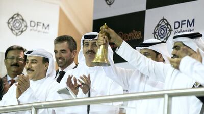Raed Al Nuaimi, CEO of Dubai Parks & Resorts rings the bell to kick off the company's IPO. To his right stands Abdulla Al Habbai, chairman of Dubai Parks & Resorts, and Essa Kazim, chairman of Dubai Financial Market (DFM). Reem Mohammed / The National