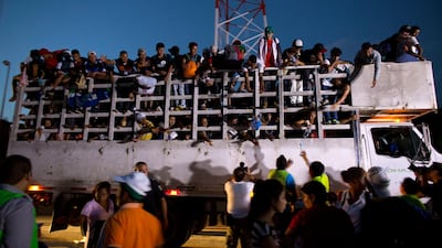 Men pass up water to Central Americans riding on the back of a truck while other migrants wait for rides, as a thousands-strong caravan of Central American makes its way toward the U.S. border, north of Pijijiapan, Mexico, at dawn on Friday, Oct. 26, 2018. Many migrants said they felt safer traveling and sleeping with several thousand strangers in unknown towns than hiring a smuggler or trying to make the trip alone.(AP Photo/Rebecca Blackwell)