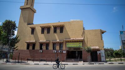 A Palestinian man wears a face mask as he rides a bicycle next to a closed mosque during a lockdown imposed following the discovery of coronavirus cases in the Gaza Strip. AP Photo