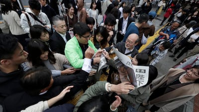 A Yomiuri newspaper worker hands a copy of the extra edition reporting the enthronement ceremony for the 59-year-old Emperor Naruhito. AP