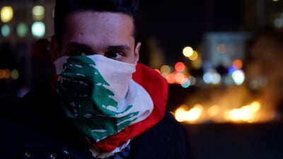 A protester covers his face with the Lebanese flag during ongoing protests at Ring Bridge in Beirut. EPA