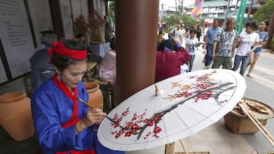 A park staff member paints designs on a souvenir umbrella at Wanda City. Rolex Dela Pena / EPA