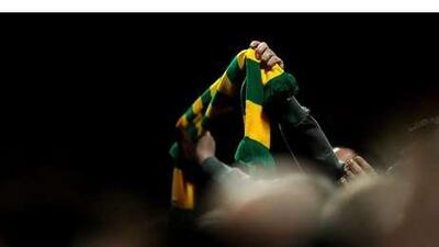 A Manchester United fan waves a green-and-gold scarf, an emblem of fan protest against the team's foreign owners.