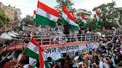 August 19 2011: Anna Hazare, left on the top of truck, waves to the crowd during a slow-moving procession to a protest venue in New Delhi, India. Thousands of supporters are moving along with Anna Hazare despite a downpour, in support of the activist's de???