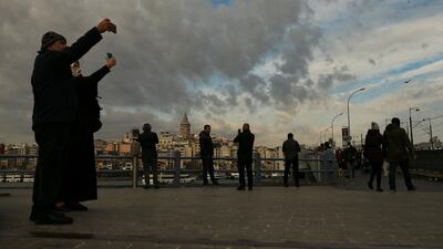 People wearing masks to help protect against the spread of coronavirus walk around the Galata Bridge hours before a two-day weekend lockdown in Istanbul. AP Photo