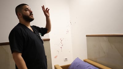 A hospital worker shows reporters the bed on which one of the men was shot to death. EPA
