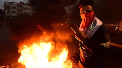 An Iraqi protester flashes the victory sign as he stands next to burning tyres set ablaze to block a street during a strike and anti-government demonstrations at the Al-Tayaran Square in central Baghdad. EPA