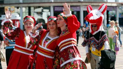 A Colombia fan with his luggage next to performers in Mordovian traditional costumes in Saransk, Russia. EPA
