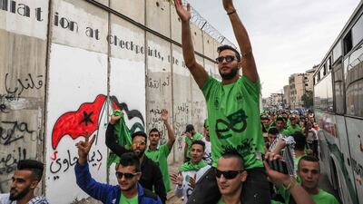 Palestinian football fans carry the Saudi flag ahead of today's match between their national football team and that of Saudi Arabia for a WC2020 qualifying match, in the Israeli occupied West Bank town of al-Ram. On the left is a section of the Israel's controversial seperation barrier. The game would mark a change in policy for Saudi Arabia, which has previously played matches against Palestine in third countries. Arab clubs and national teams have historically refused to play in the West Bank, where the Palestinian national team plays, as it required them to apply for Israeli entry permits. AFP