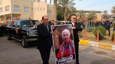 Mourners transport the flag-draped coffin of Iraqi archaeologist, Lamia al-Gailani, seen in the poster, for burial during her funeral procession in the National Museum in Baghdad, Iraq. AP