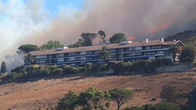 Smoke rises from a burning mountainside behind a building in Cape Town. Chantal Louw / via Reuters