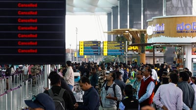 Travellers look at updates on flights, as they stand next to a screen displaying details of cancelled IndiGo airlines flights, at Kempegowda International Airport in Bengaluru, India, on December 6, 2025. Reuters