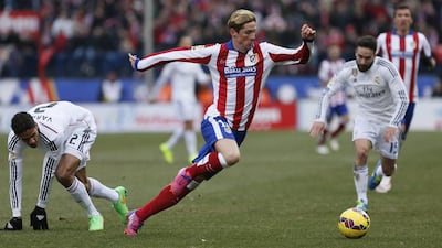 Atletico Madrid striker Fernando Torres dribbles away from Real Madrid defender Raphael Varane, left, during their La Liga match on Saturday. Juanjo Martin / EPA