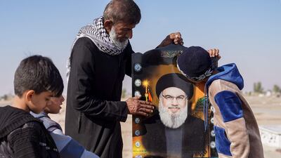 A man and children pray by a symbolic grave for murdered Hezbollah leader Hasan Nasrallah in Iraq's Shiite holy city of Najaf. AFP