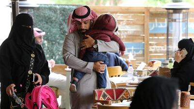 A Saudi man carries his son as they sit a at cafe in Riyadh. Reuters