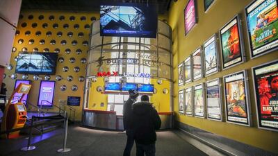 People look at the movie choices available at a cinema as Quebec allows the reopening of movie theatres but not the selling of food and drinks, which includes popcorn, during the outbreak of the coronavirus disease in Montreal, Canada. Reuters