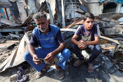 Mohammed Al Dalou, right, near the scene of the Israeli strike that caused the fire in which his brother and mother died. Reuters