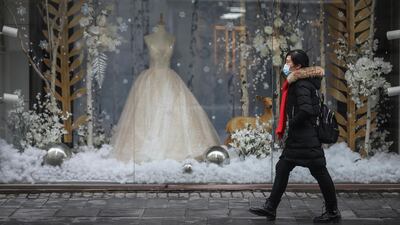 A woman wears a mask while passing in front of wedding shop in Wuhan, China, where the coronavirus originated. Courtesy: Getty Images
